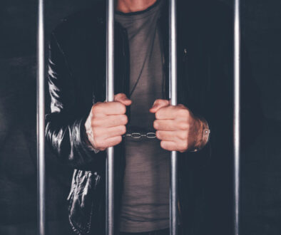 Handcuffed man behind prison bars